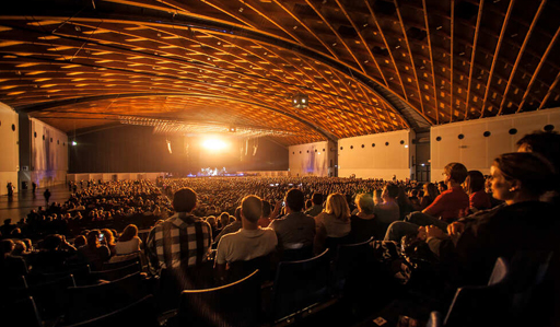 Menschen sitzen bei Konzert auf einer Tribï¿½ne.