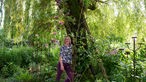 Hildegard Rave lehnt an einem Baum. 