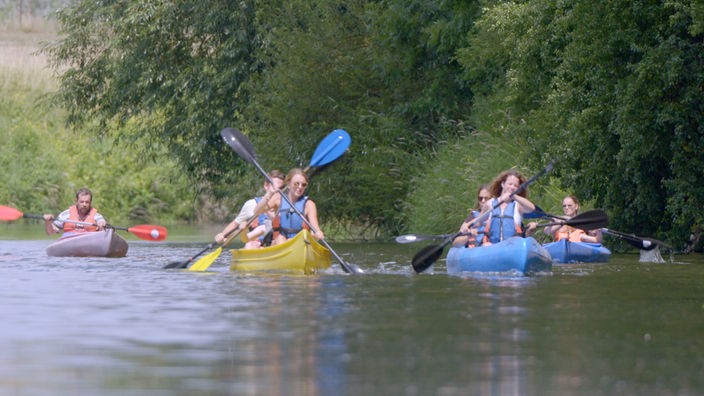 Menschen in Kanus paddeln auf einem Fluss