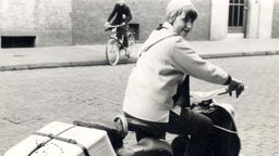 Ursula Schlüter auf einem Roller mit Koffer