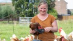 Stephie Bönniger mit einem Huhn auf dem Arm.