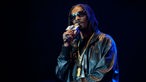 Snoop Dop mit Sonnenbrille, Goldkettchen und glitzerndem Mikrofon