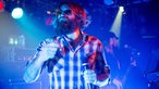 Der Sänger mit Mikrofon in der Hand im blauen Scheinwerferlicht