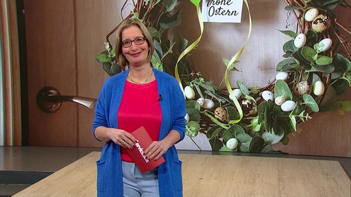 Das Bild zeigt Yvonne Willicks im Servicezeit-Fernsehstudio. Im Hintergrund ist ein Osterkranz abgebildet.