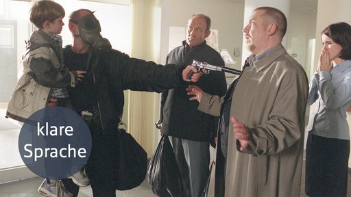 Bild mit "klare Sprache"-Logo: Ein Entführer bedroht Hauptkommissar Freddy Schenk mit einer Pistole