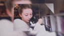 Blonde Frau schmust mit einer Katze mit schwarz-weißem Fell 