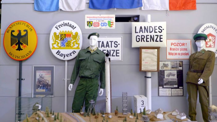 Grenzschilder und Soldatenfiguren in Uniform in einer Ausstellung