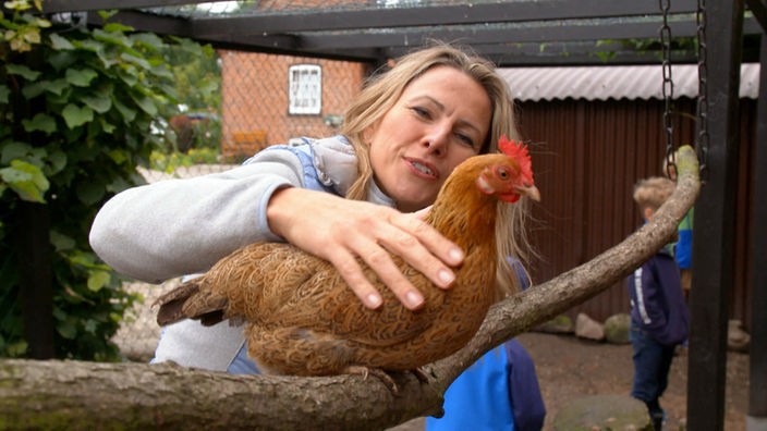Andrea Grießmann streichelt ein braunes Huhn