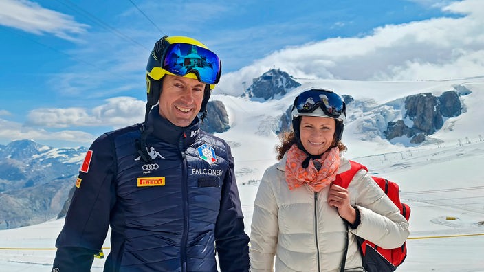 Anne Willmes (r) mit dem mehrfachen Speedski-Weltmeister Simone Origone in Skikleidung auf einem schneebedeckten Berg