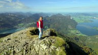 Tamina Kallert steht auf dem Gipfel des Schafbergs mit Blick auf die Bergseen.