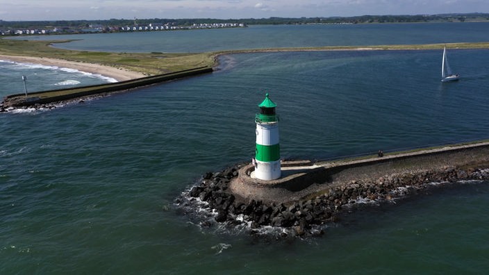 Kleiner grün-weißer Leuchtturm auf einer vorgelagerten künstlichen Insel