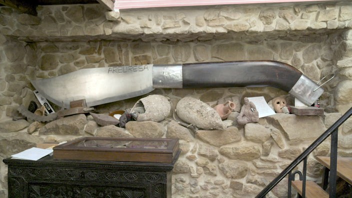 Ein riesiges Modell eines Messers hängt an einer Steinwand