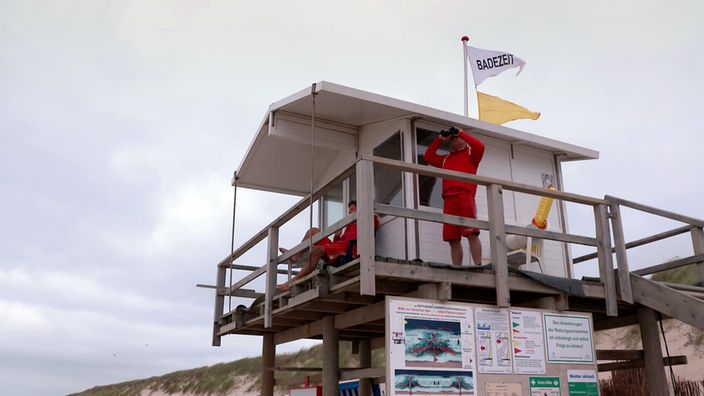 Rettungsschwimmerhäuschen am Strand mit gelber Fahne auf dem Dach