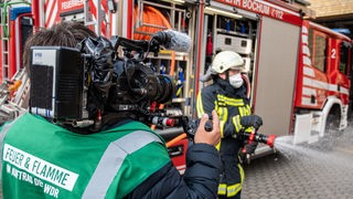 Kameraman vor Feuerwehrwagen über die Schulter gezeigt