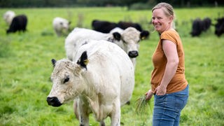 Stephie Bönniger auf der Weide mit Rindern. 